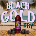Black Gold Dry wine bottle with text and berries on a wooden surface with palm leaves.