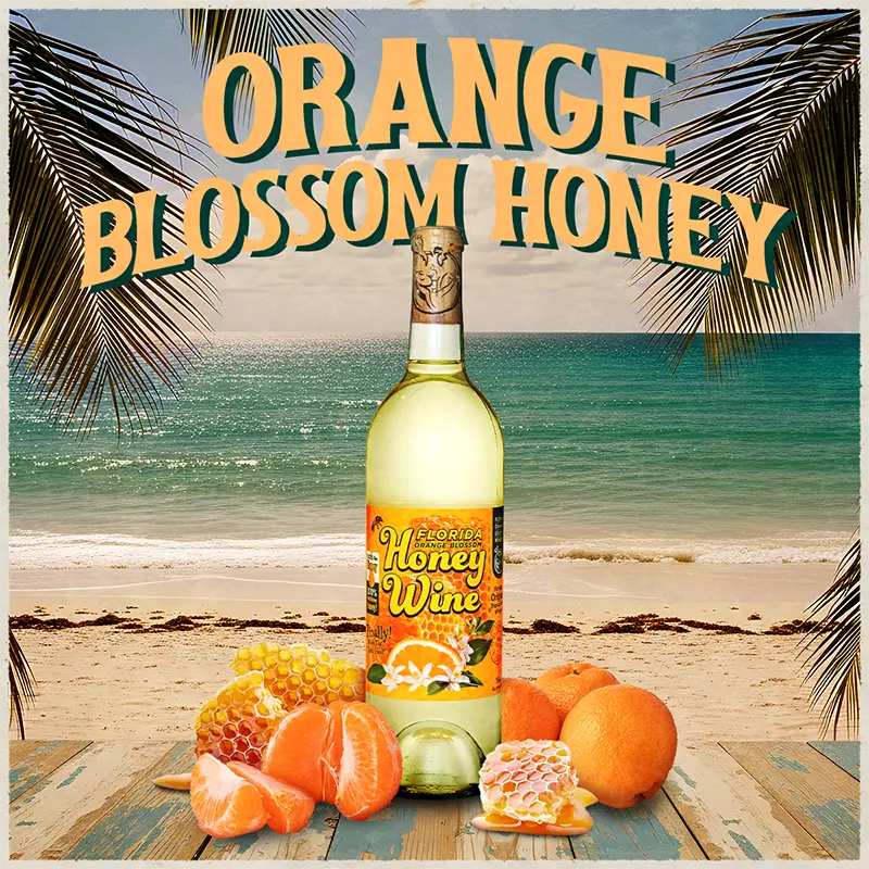 Bottle of orange blossom honey wine with fruits and honeycomb on a beach background