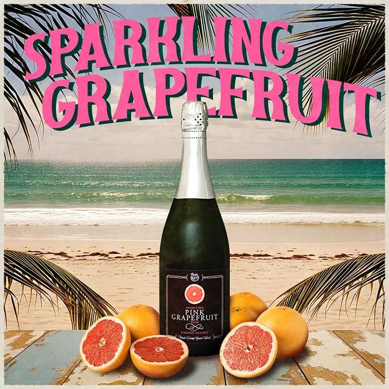 Bottle of sparkling grapefruit wine with pink grapefruits on a beach setting