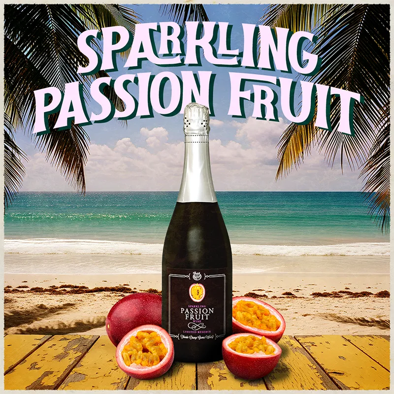 Bottle of sparkling passion fruit wine on a beach with palm trees and ocean in the background.