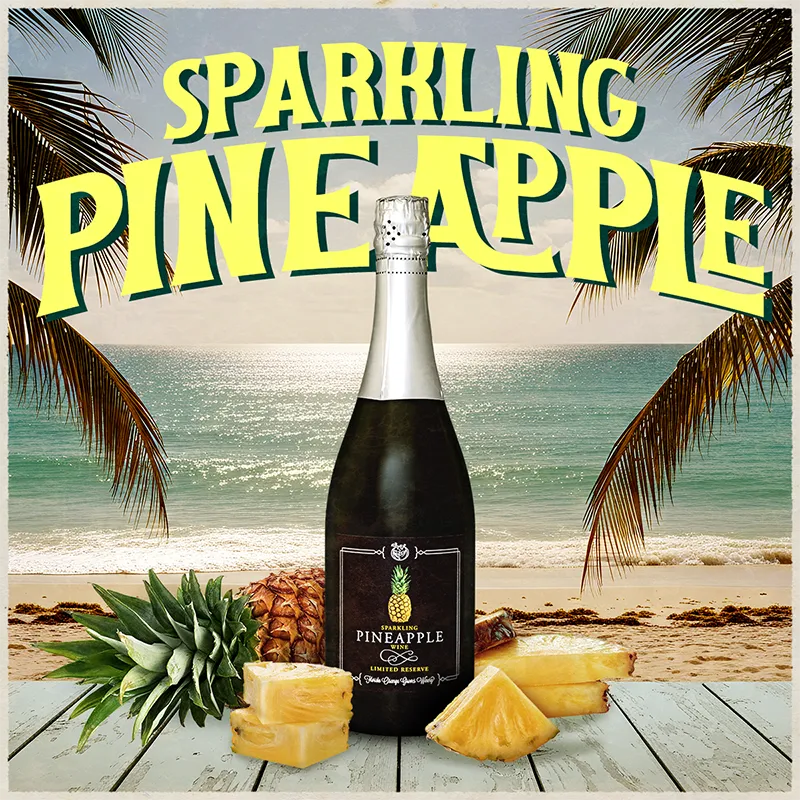 Bottle of sparkling pineapple wine with pineapples on a beach setting